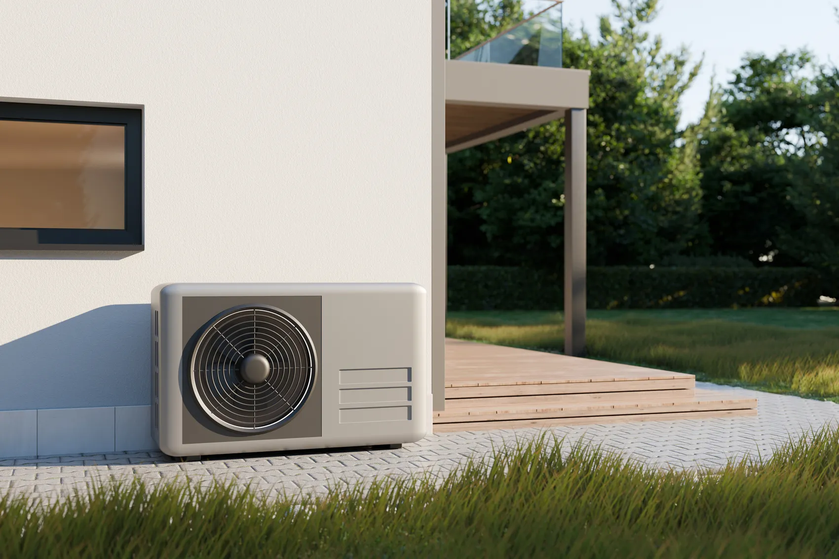 Wärmepumpe an der Außenwand eines modernen Hauses mit Garten im Hintergrund.