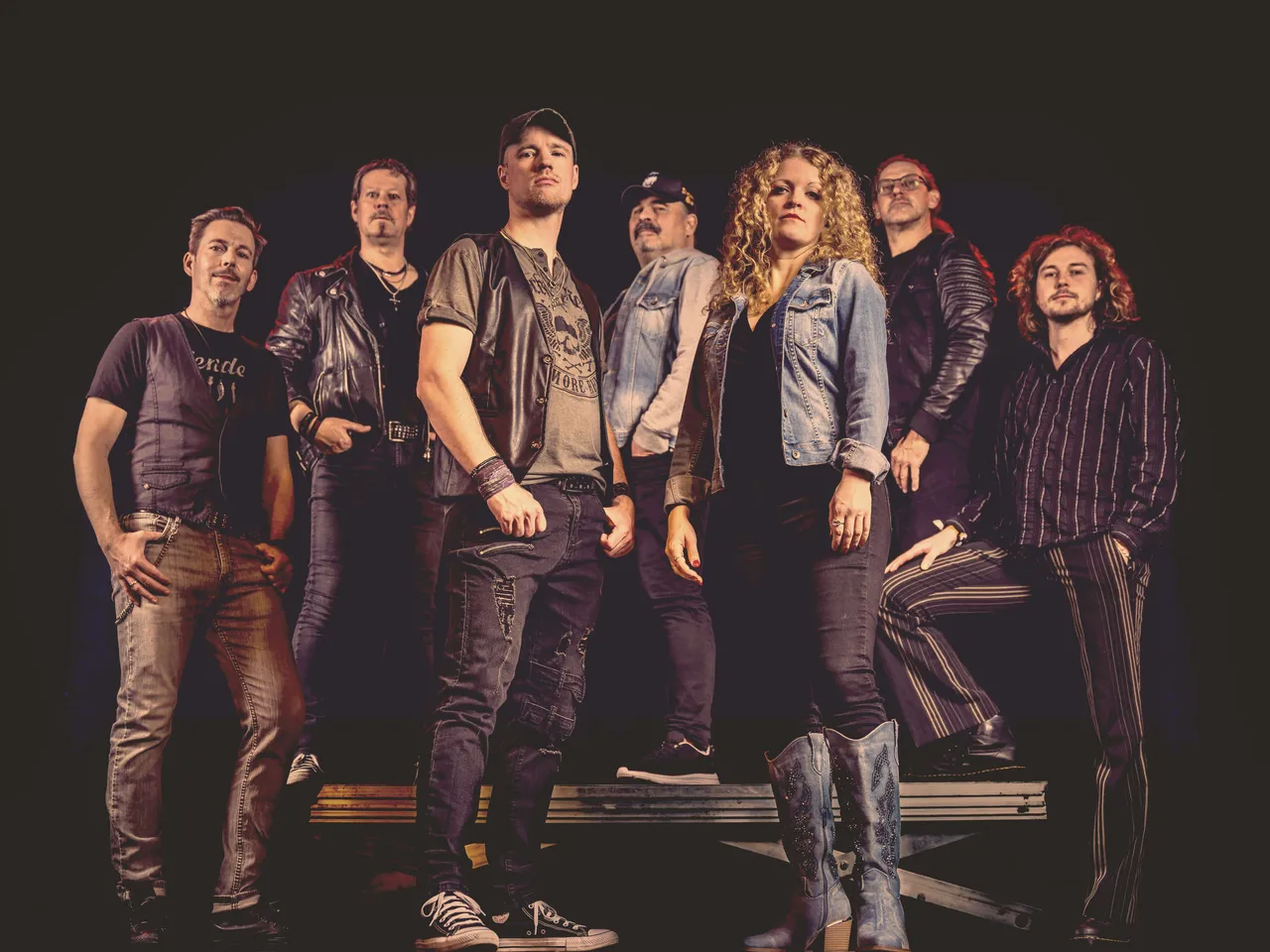 Sieben Musiker der Coverband Rockwood posieren für ein Pressefoto. Die Band spielt Rockhits aus den 70er, 80er und 90er Jahren.