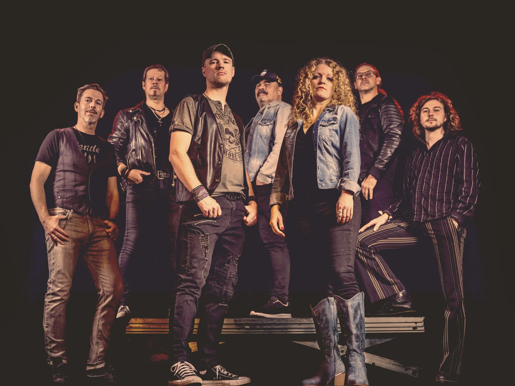 Sieben Musiker der Coverband Rockwood posieren für ein Pressefoto. Die Band spielt Rockhits aus den 70er, 80er und 90er Jahren.