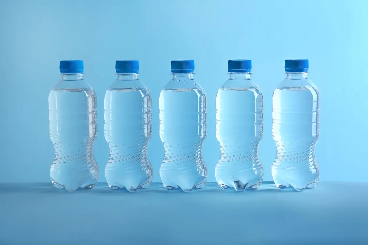 Reihe aus fünf Plastikwasserflaschen vor blauem Hintergrund. Die Spende soll wohnungslosen Menschen in Hagen bei der aktuellen Hitze helfen.