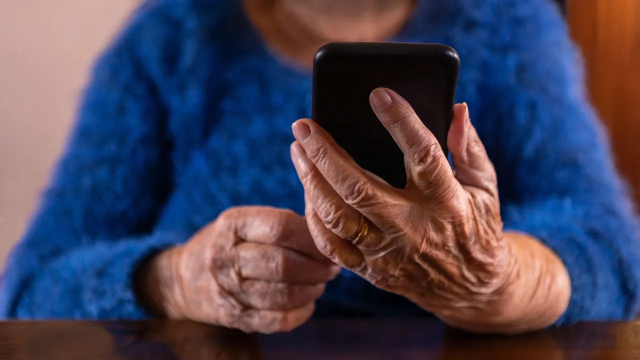 Hände einer älteren Person bedienen ein Smartphone. Symbolbild für Betrug am Telefon.