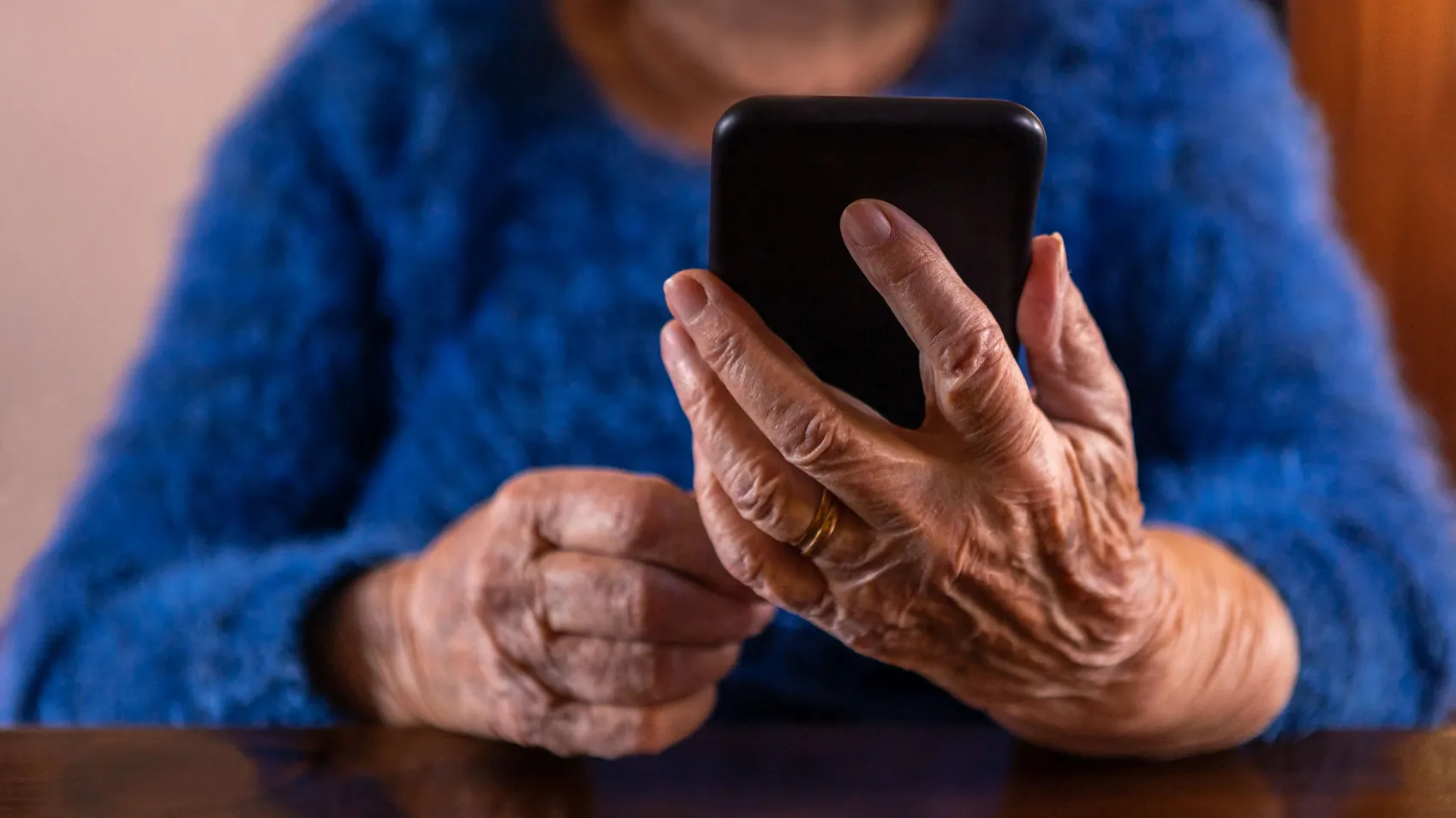 Hände einer älteren Person bedienen ein Smartphone. Symbolbild für Betrug am Telefon.