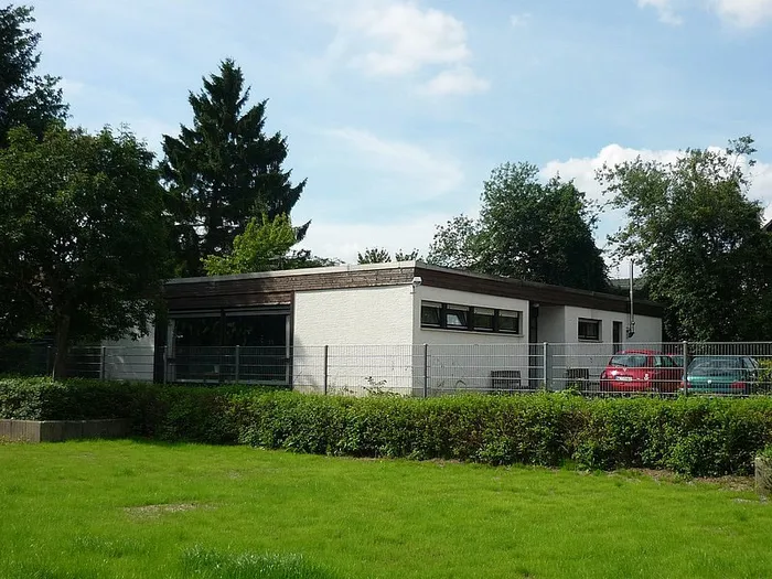 Das flache, weiße Gebäude der Begegnungsstätte „Sonnentreff“ hinter einem Metallzaun und einer grünen Hecke.