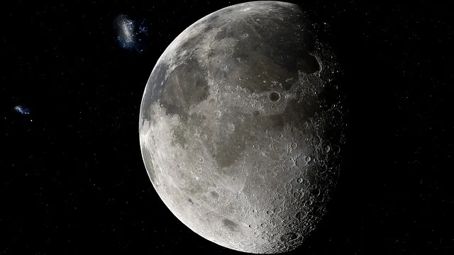 Halbe Mondsichel mit Kratern vor Sternenhimmel und Galaxien.