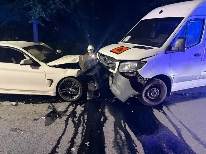 Ein weißer PKW und ein weißer Transporter sind nach einer Kollision mit Frontschäden auf der Fahrbahn verkeilt, während sich Öl auf dem Asphalt ausbreitet.