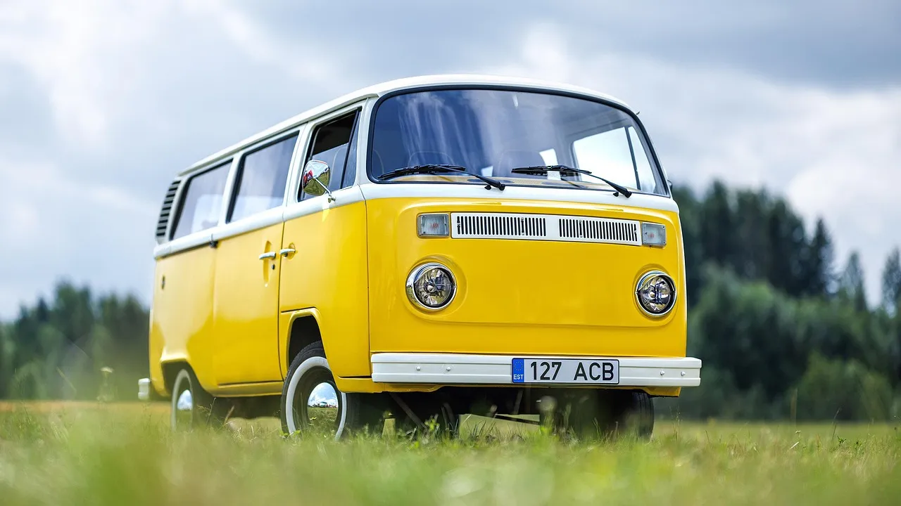 Gelber VW-Bus im Stil der 1960er-Jahre steht auf einer Wiese, Kennzeichen 127 ACB.