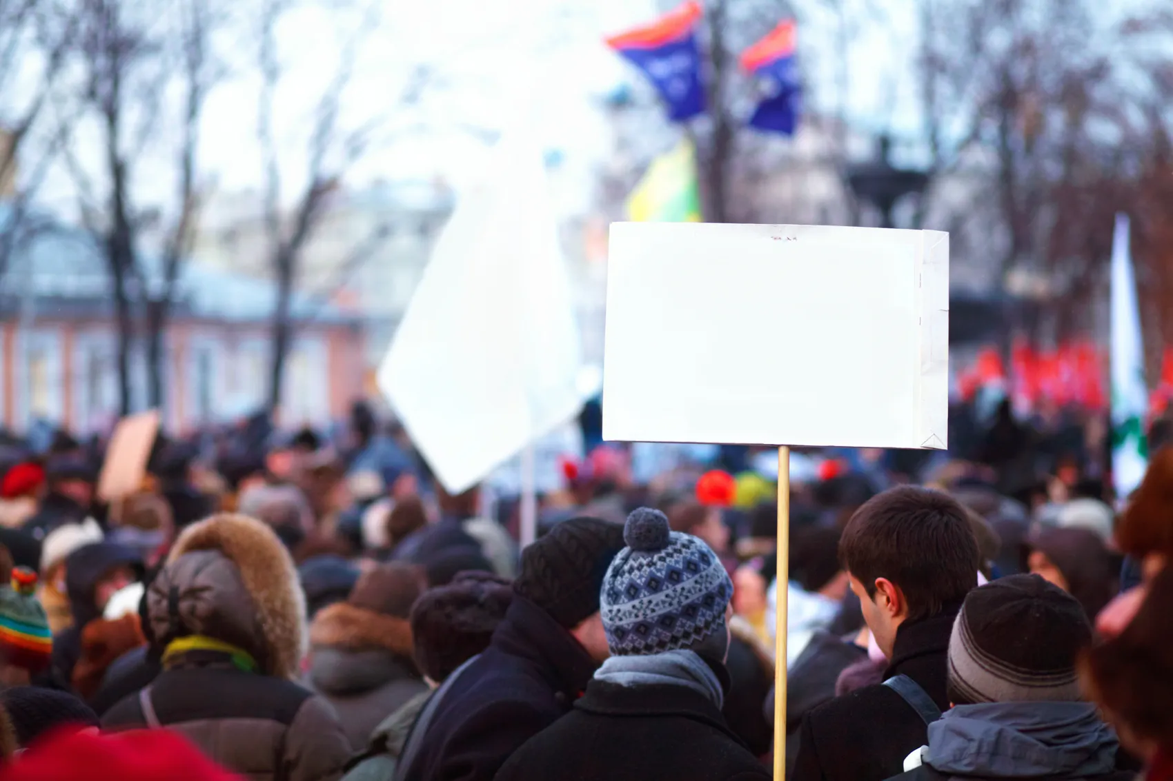 Menschenmenge bei einer Demonstration, im Vordergrund hält jemand ein leeres Schild hoch.