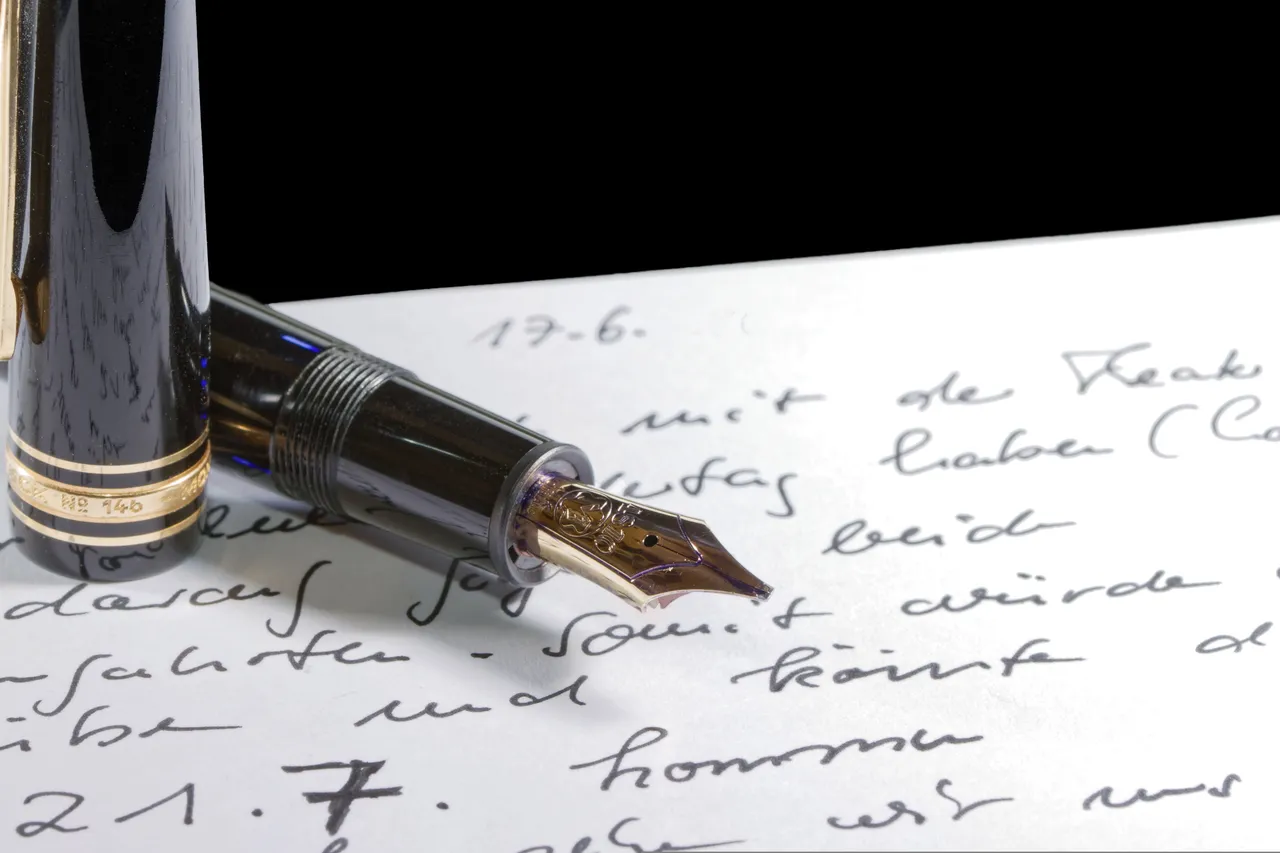 Nahaufnahme einer Füllfederhalter-Spitze auf einem Blatt Papier mit handschriftlichem Text.