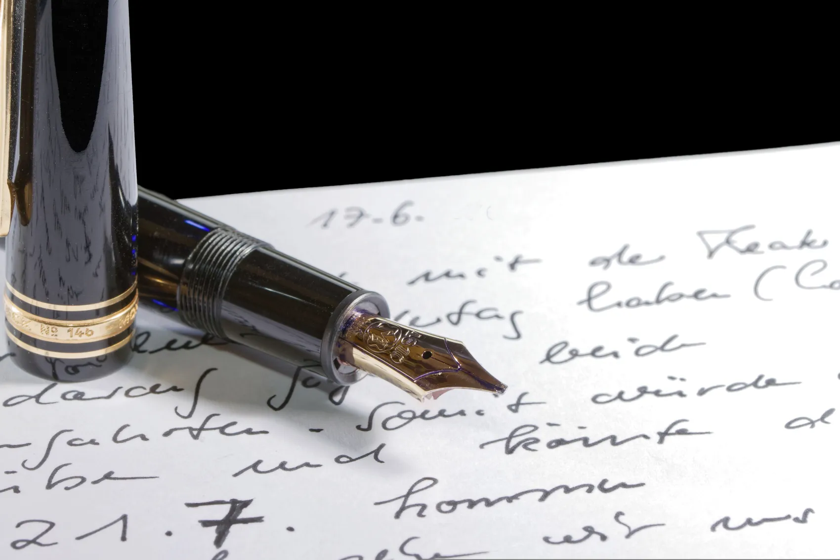 Nahaufnahme einer Füllfederhalter-Spitze auf einem Blatt Papier mit handschriftlichem Text.