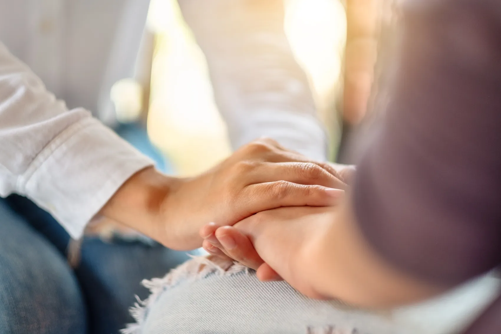 Zwei Hände halten sich, um Trost und Mitgefühl auszudrücken.